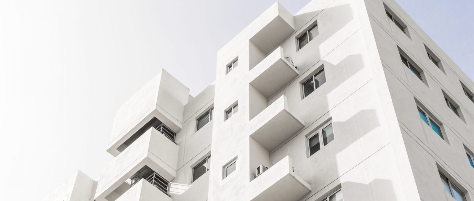 A low angle shot of a facade of a white modern building under a blue clear sky